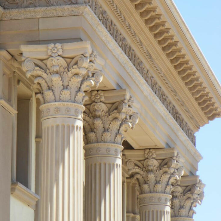 Les 4 piliers du contrat de construction en Algérie – symbole architectural Quatre piliers romains représentant les quatre bases essentielles d’un contrat de construction réussi en Algérie selon un architecte algérien